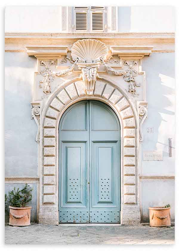 Cuadro de puerta romana azul suave con fachada clásica beige, relieves ornamentales, arco de piedra y macetas de terracota, de estilo fotográfico. Disponible en kudeko.com