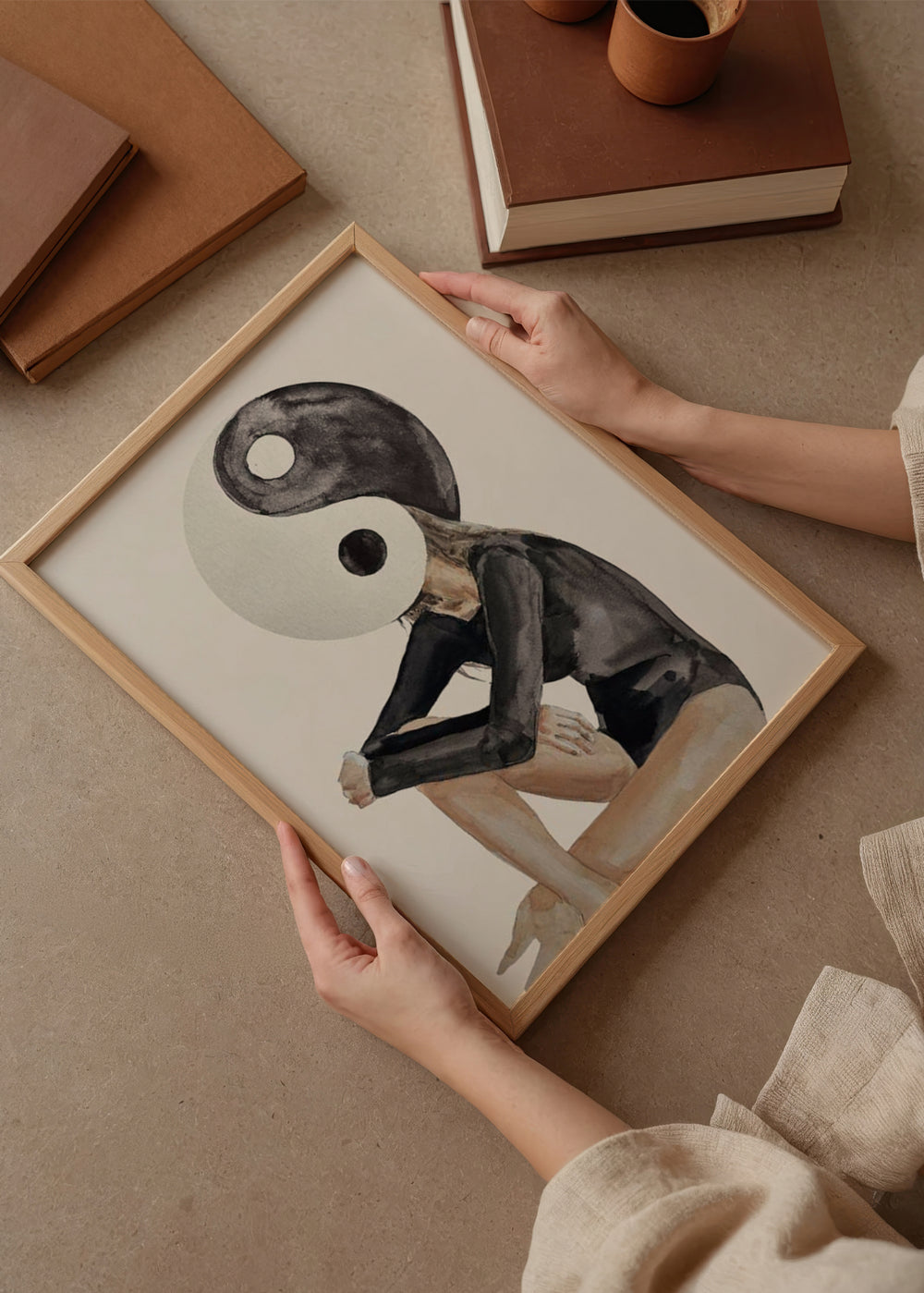 Tableau encadré avec figure féminine assise, tête yin yang noire et blanche, corps en beige et gris foncé, dans un style illustration contemporain sur fond clair. Disponible sur kudeko.com