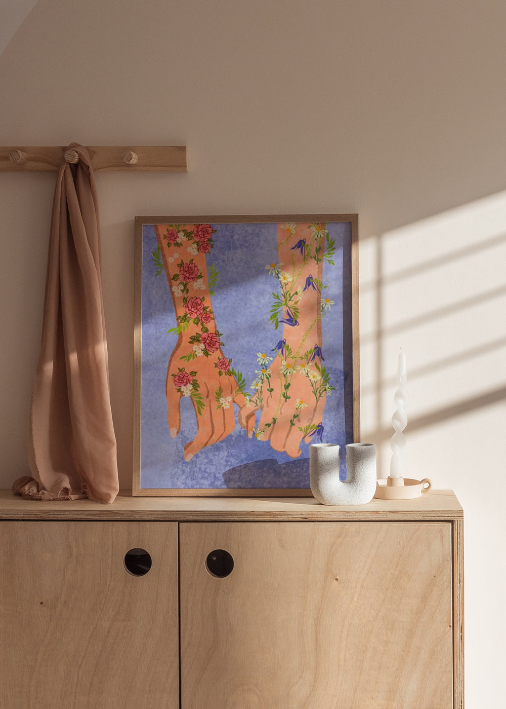 Quadro com duas mãos entrelaçadas, flores cor-de-rosa, margaridas brancas, campainhas azuis, fundo azul suave e estilo de ilustração poético. Disponível em kudeko.com