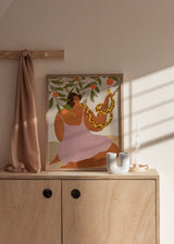 Gerahmtes Wandbild mit sitzender Frau zwischen Orangenzweigen, Orangen, gelber gefleckter Schlange, Erdtönen, Olivgrün, Creme und Altrosa, im symbolischen Illustrationsstil. Erhältlich auf kudeko.com