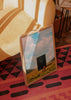 Gerahmtes Wandbild mit einem Erwachsenen und einem Kind vor einem Sternenportal, goldenes Feld, blauer Himmel, weiche Wolken und surrealer Illustrationsstil in Ocker, Creme und Blau. Erhältlich auf kudeko.com