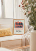 Quadro emoldurado com a fachada de Petra na Jordânia, em tons coral, azul-escuro e rosa suave, com composição arquitetónica em estilo de ilustração, tipografia e coordenadas geográficas. Disponível em kudeko.com