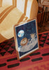 Tableau avec lion et girafe en astronautes dans un vaisseau spatial, fond bleu nuit étoilé, planète bleu clair, tons beige et blanc, style enfantin doux. Disponible sur kudeko.com