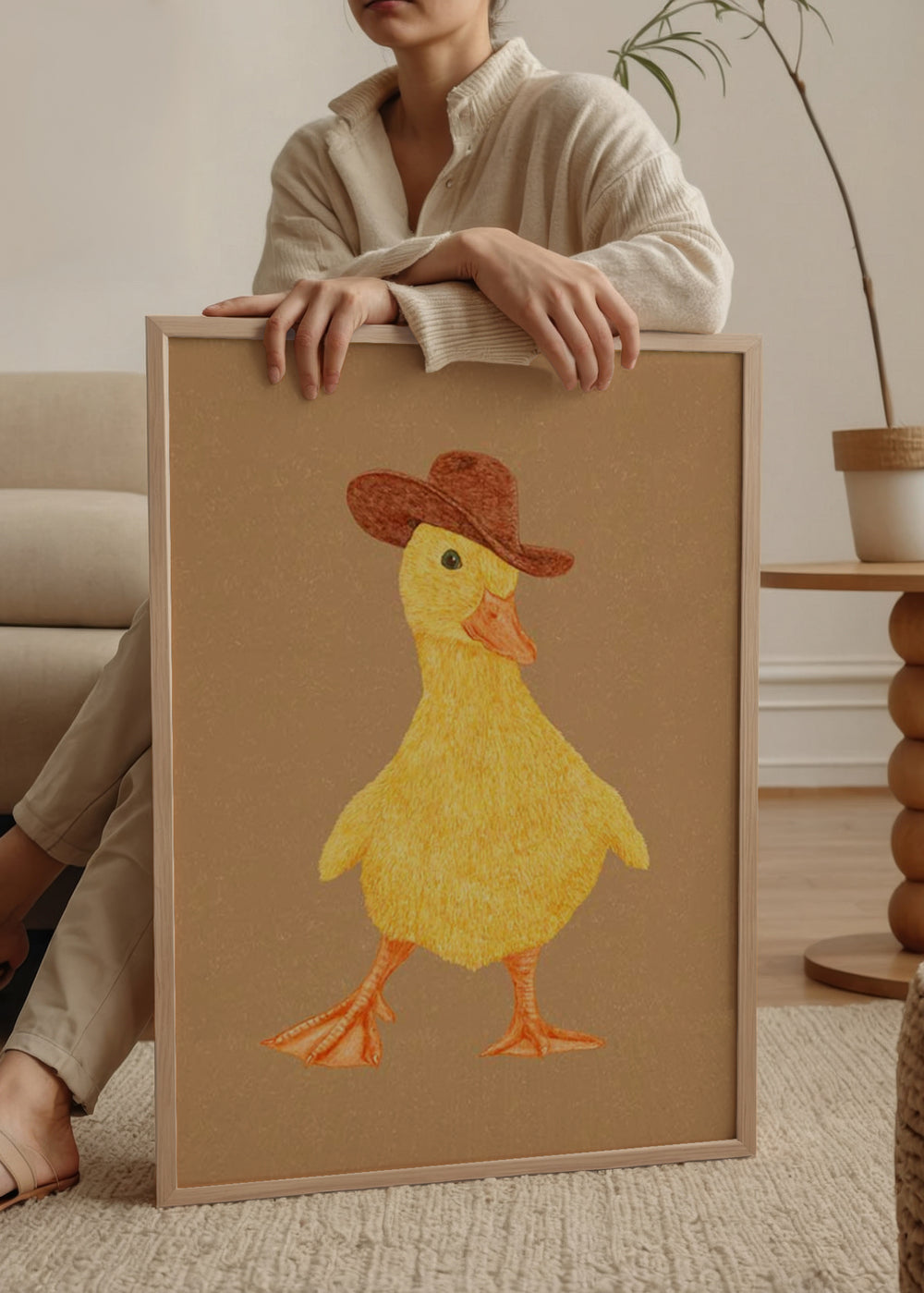 Wandbild mit gelbem flauschigem Entchen, braunem Cowboyhut, orangem Schnabel, orangefarbenen Füßen, beigem Hintergrund und kindgerechtem, warmem Stil. Erhältlich auf kudeko.com