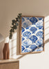 Gerahmtes Wandbild mit wiederholtem Muschelmotiv in Kobaltblau, Hellblau und Weiß, im küstennahen Illustrationsstil auf hellem Hintergrund. Erhältlich auf kudeko.com