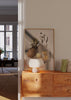 Wandbild mit Ananas und gelben Zitronen in einem beigen Netzbeutel, auf hellem Hintergrund mit weichen Schatten, im natürlichen fotografischen Stil und warmem Licht. Erhältlich auf kudeko.com