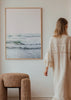 Tableau représentant une mer calme avec vagues douces, écume blanche, rivage clair, ciel rose poudré, tons sable, blanc et vert d’eau, dans un style photographique. Disponible sur kudeko.com