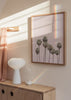 Quadro emoldurado com palmeiras altas sobre fundo rosa empoeirado, tons verdes suaves, bege claro e estilo fotográfico tropical sereno e luminoso. Disponível em kudeko.com