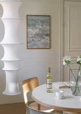 Tableau avec vagues de la mer se brisant sur le rivage, écume blanche, eau bleu gris et reflets doux, dans un style photographique apaisant. Disponible sur kudeko.com