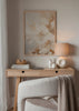 Quadro emoldurado de grandes flores em tons de creme, bege e caramelo claro, com composição suave, formas difusas e estilo floral etéreo e luminoso. Disponível em kudeko.com