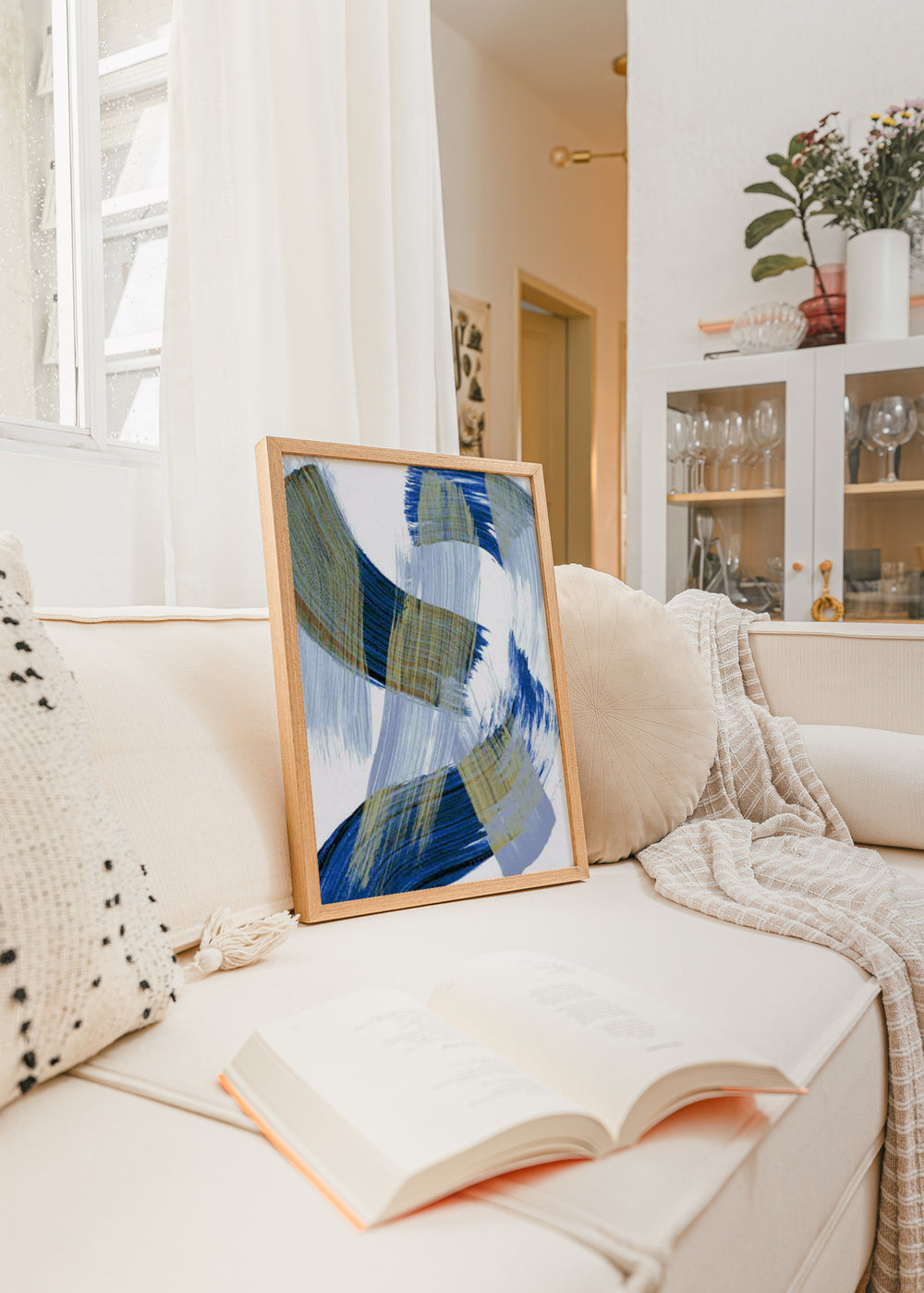 Gerahmtes Wandbild mit abstrakter Komposition aus überlagerten geschwungenen Formen in Blau, Olivbeige und Hellgrau auf weißem Hintergrund, im zeitgenössischen abstrakten Stil. Erhältlich auf kudeko.com