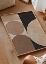 Quadro emoldurado com formas geométricas, semicírculos e arcos em bege, areia e castanho sobre fundo preto, num estilo contemporâneo equilibrado e depurado. Disponível em kudeko.com