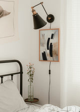 Tableau encadré avec composition abstraite de formes noires courbes, lignes fines, fond beige, écru et nuances terre, dans un style contemporain épuré. Disponible sur kudeko.com