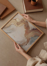 Quadro emoldurado com composição abstrata de formas fluidas em branco pérola, bege, dourado, terracota e cinzento fumo, de estilo mineral e contemporâneo. Disponível em kudeko.com