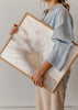 Wandbild mit abstrakter Komposition aus fließenden Formen in Off-White, sanftem Grau und goldenen Details in mineralischer Anmutung, moderner abstrakter Stil als gerahmte Wanddekoration. Erhältlich auf kudeko.com
