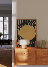 Quadro emoldurado com forma orgânica amarela sobre fundo preto, linhas onduladas marfim e composição abstrata de estilo moderno para decoração de parede. Disponível em kudeko.com