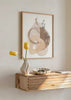 Quadro emoldurado com composição abstrata de formas orgânicas em bege, areia, taupe, cobre suave, pontos pretos e fundo branco, de estilo abstrato minimalista. Disponível em kudeko.com