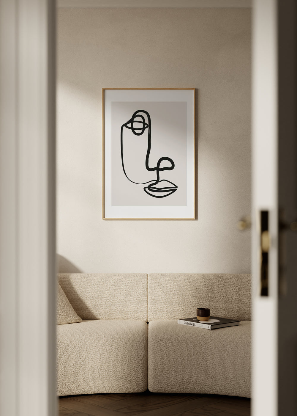 Tableau encadré avec visage abstrait en ligne noire sur fond beige clair, œil circulaire, nez courbe, lèvres marquées et style abstrait minimaliste. Disponible sur kudeko.com