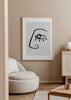 Quadro emoldurado com rosto abstrato, olho central destacado, linha preta contínua sobre fundo bege claro, num estilo abstrato de formas depuradas e contemporâneas. Disponível em kudeko.com