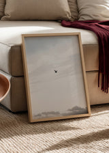 Minimalistisches Wandbild eines fliegenden Vogels am Himmel, ideal für eine ruhige und elegante Dekoration. Erhältlich auf kudeko.com