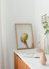Quadro minimalista de uma mão segurando uma maçã verde. Disponível em kudeko.com.