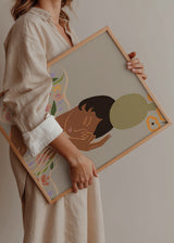 Wandbild mit liegender nachdenklicher Frau, transparentem Kleid mit Blumenmuster, grüner Vase mit korallenfarbenen Blumen, beigem Hintergrund und illustrativem Stil. Erhältlich auf kudeko.com