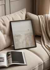 Quadro costeiro minimalista em tons de bege, branco pérola e areia, com figura solitária a caminhar junto à água e estilo abstrato depurado. Disponível em kudeko.com
