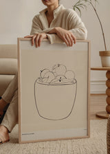 Wandbild mit Schale voller runder Früchte und Blätter, feine schwarze Linien auf hellbeigem Grund, minimalistische Komposition mit klarer, ruhiger Formsprache. Erhältlich auf kudeko.com