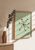 Gerahmtes Wandbild mit kleinen dunkelbraunen Blüten, geschwungenen Stielen, mintgrünem Hintergrund, weißen Details und orangefarbenen Akzenten in floralem, ruhigem Stil. Erhältlich auf kudeko.com