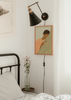 Cuadro decorativo de estilo minimalista y orgánico colocado en dormitorio, ilustración serena de mujer abrazando una hoja tropical, modelo The Introvert