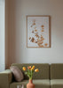 Gerahmtes Wandbild mit Eukalyptuszweigen in Gold, Beige und sanftem Kupfer auf hellem Hintergrund, im leichten botanisch-floralen Stil gestaltet. Erhältlich auf kudeko.com