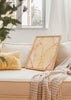 Cuadro decorativo de estilo minimalista y orgánico colocado en salón, hojas abstractas en tonos cálidos, modelo Hojas de Luz