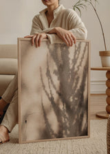 Wandbild mit Schatten von Zweigen auf eine Wand mit warmer Textur projiziert, schlichter Stil und natürliche dekorative Wirkung. Erhältlich auf kudeko.com
