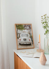 Cuadro decorativo de estilo minimalista y sereno colocado en salón, fotografía vintage de coche clásico en calle europea, modelo Driving Cascais