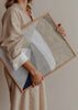 Quadro com composição abstrata de formas curvas sobrepostas em bege, areia, cinzento claro, branco quebrado e azul-marinho, de estilo contemporâneo depurado. Disponível em kudeko.com