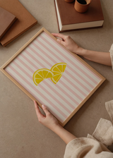 Cuadro decorativo de estilo minimalista y tonos_pastel colocado en cocina, rodajas de limón sobre fondo de rayas rosas, modelo Limones Fresquitos