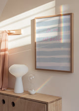 Quadro emoldurado com frase La vie est belle, riscas horizontais em azul céu e branco, tipografia rosa suave e estilo tipográfico contemporâneo para quarto ou zona de toucador. Disponível em kudeko.com