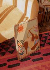 Cuadro decorativo de estilo orgánico y colorido colocado en salón, figura femenina con arco en paisaje surrealista, modelo Bow And Arrow