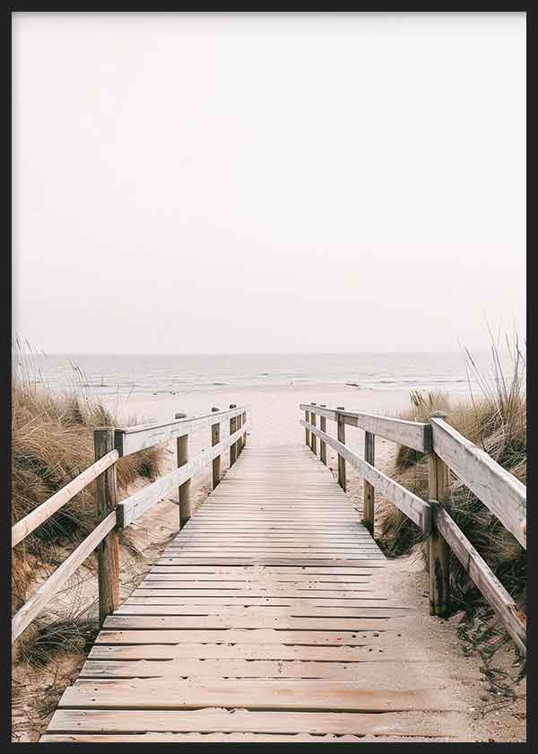 Cuadro de pasarela de madera hacia la playa entre dunas, con mar sereno, cielo claro, tonos arena, beige y gris suave, de estilo fotográfico. Disponible en kudeko.com