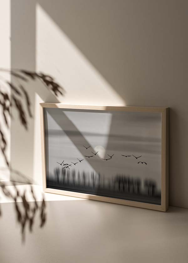 Tableau horizontal avec oiseaux noirs en vol au-dessus d’arbres estompés, lune discrète, ciel gris et style nature paysager apaisant. Disponible sur kudeko.com