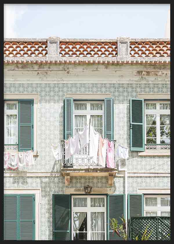 Cuadro de fachada portuguesa con azulejos claros, balcón central, ropa tendida, ventanas con contraventanas verdes y tejado terracota, de estilo fotográfico. Disponible en kudeko.com