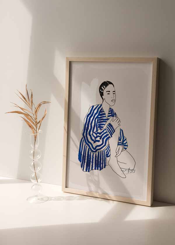 Cuadro de ilustración artística de mujer con camisa de rayas azules sobre fondo beige. Una obra cargada de estilo.