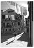 Cuadro escena urbana en blanco y negro con niña saltando a la comba, edificios antiguos, ropa tendida y fuerte luz lateral, de estilo fotográfico. Disponible en kudeko.com