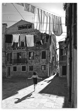 Cuadro escena urbana en blanco y negro con niña saltando a la comba, edificios antiguos, ropa tendida y fuerte luz lateral, de estilo fotográfico. Disponible en kudeko.com