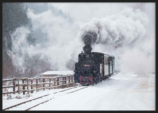 Cuadro horizontal de locomotora de vapor negra sobre vías nevadas, con humo blanco denso, paisaje invernal en grises y estilo fotográfico. Disponible en kudeko.com