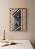 Cuadro de mujer en balcón de edificio urbano, en tonos blanco y negro, con barandillas metálicas, escena cotidiana y estilo fotográfico. Disponible en kudeko.com
