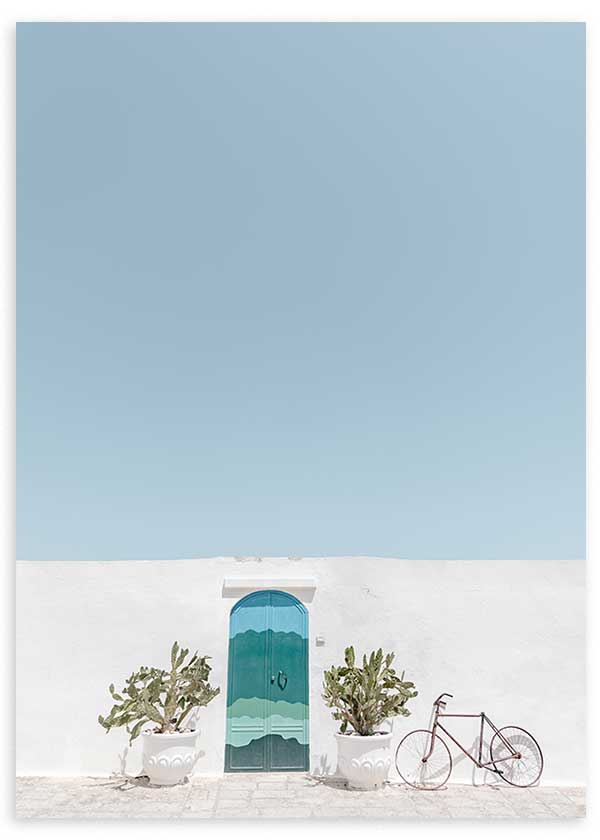 Quadro com porta azul turquesa em fachada branca, vasos simétricos, bicicleta leve, céu azul claro e estilo fotográfico mediterrânico sereno. Disponível em kudeko.com