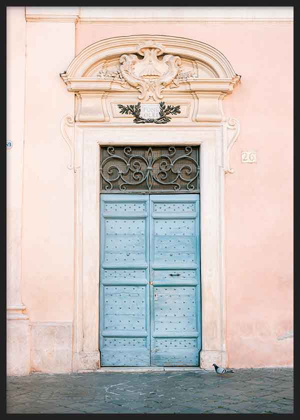 Cuadro de puerta antigua azul pastel sobre fachada rosa empolvado, con molduras clásicas, reja ornamental y estética urbana de estilo fotográfico. Disponible en kudeko.com