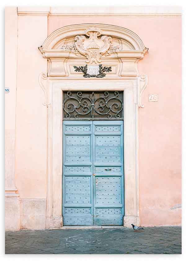 Wandbild mit alter pastellblauer Tür vor puderrosa Fassade, klassischen Stuckdetails, Ziergitter und urbaner Bildsprache im fotografischen Stil. Erhältlich auf kudeko.com