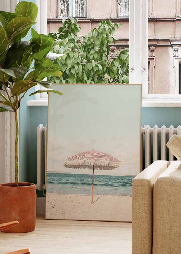 Decoración con cuadros, ideas - Cuadro fotográfico de sombrilla rosa en la playa. Una obra muy veraniega. Elige el tamaño y enmarcación que mejor vaya a tus paredes.